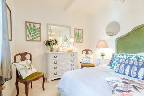 A bedroom with a bed, a dresser, a chair, a nightstand, a mirror, and a lamp.