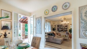 A spacious living area with a dining table set for a meal, a cozy seating area with a sofa, and a well-lit room with a chandelier. - Beautiful Villa Lory on the hills of Lucca (Segromigno in Monte)