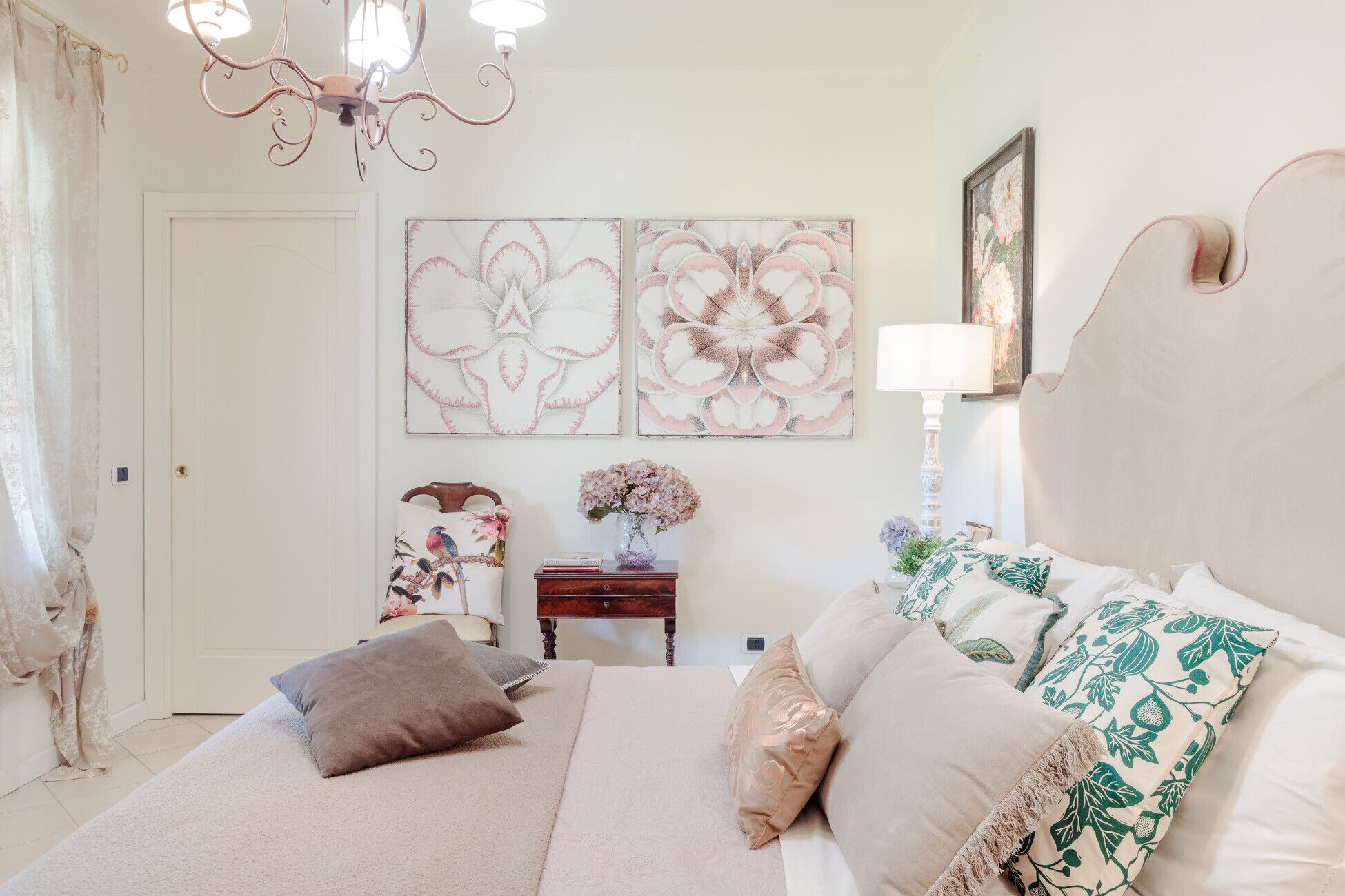 Een slaapkamer met een bed, kussens, een nachtkastje, een lamp en twee decoratieve wandpanelen.