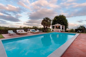 A swimming pool with lounge chairs and a gazebo.