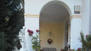 Un patio con una estatua, plantas en macetas y un banco.