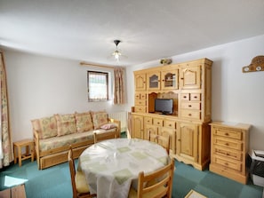 A cozy room with a wooden sofa, a round table, and a TV on a wooden cabinet. - Les Menuires: 3 rooms, 5 pers, 30m², ski-in/ski-out (Les Menuires)