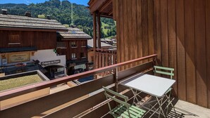 A balcony with a wooden railing, a table, and chairs. - Cozy studio 4 pax - Station center in La Clusaz (La Clusaz)