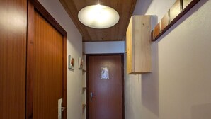 A narrow hallway with wooden doors and a ceiling light fixture. - Cozy studio 4 pax - Station center in La Clusaz (La Clusaz)