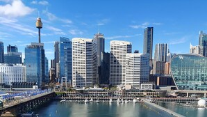 A cityscape with modern skyscrapers, a prominent tower, and a waterfront promenade with boats. -  Luxury 2 bedroom apartment Sydney, Darling Harbour, ICC and free secure parking (Sydney)