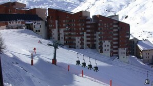 Une station de ski dotée d'un télésiège, de bâtiments et offrant une vue sur une montagne enneigée.