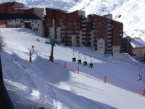 Una stazione sciistica con una seggiovia, edifici e una montagna innevata sullo sfondo.