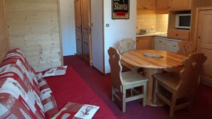 Un salon chaleureux avec un tapis rouge, des meubles en bois et un coin repas comprenant une table et des chaises en bois.