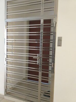 Porta de metal com estrutura em barras horizontais, olho de fechadura e tranca.