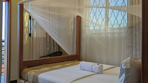 Una habitación de hotel con una cama, una mesita de noche con teléfono y una ventana con vistas.
