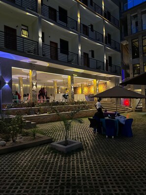 Un hotel de varios pisos con asientos al aire libre y un patio bien iluminado.