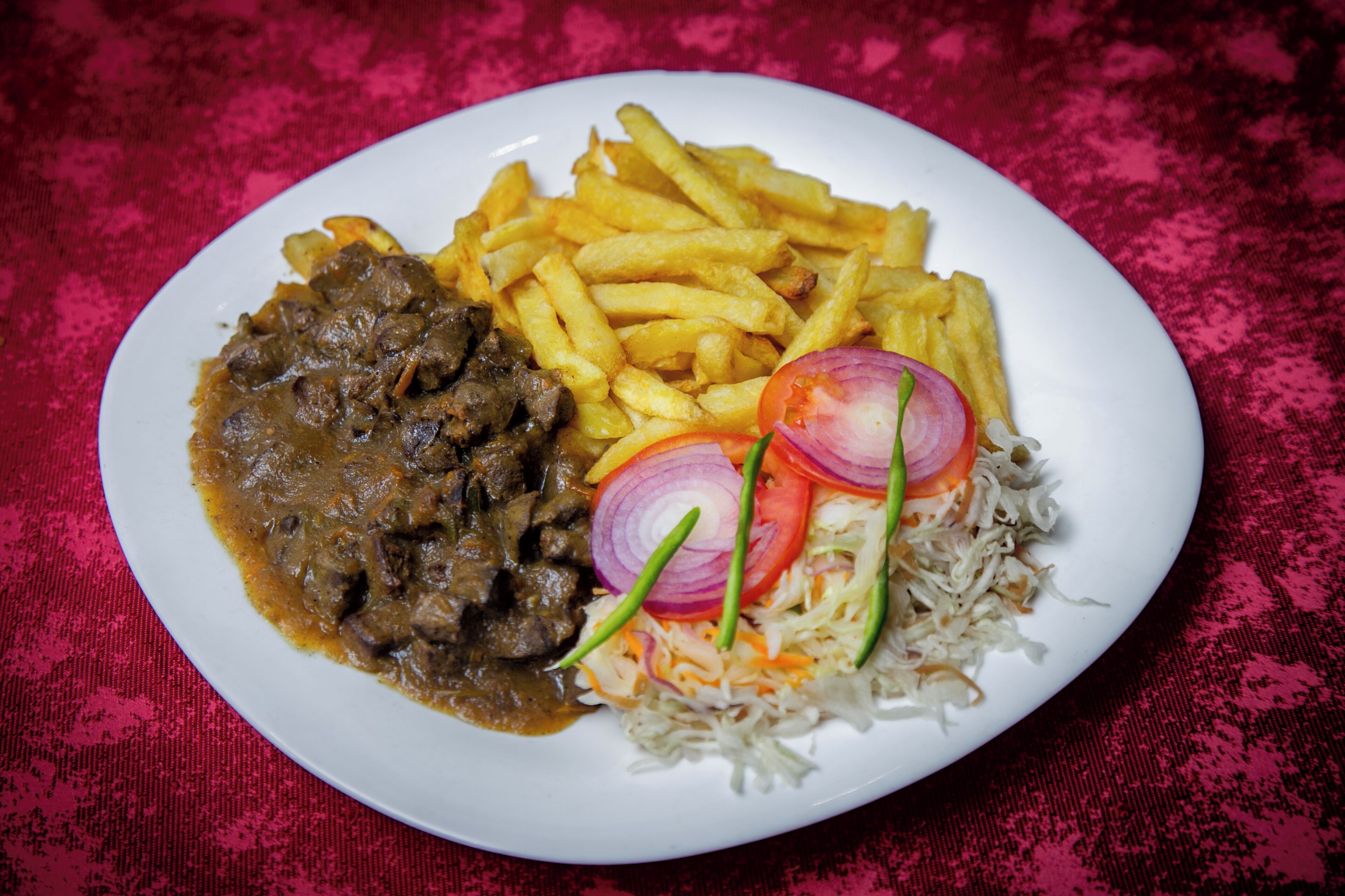 A plate of food with French fries, a meat dish, and a side of coleslaw.
