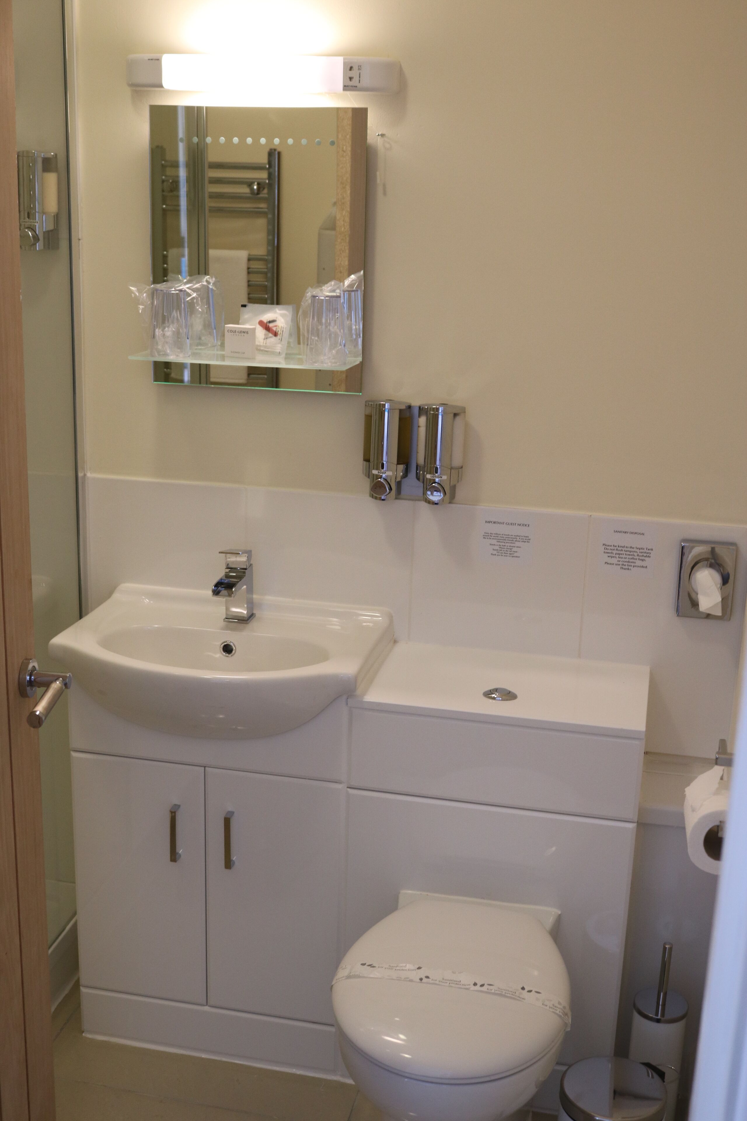 Un bagno con lavandino, specchio, servizi igienici e un piccolo cestino.
