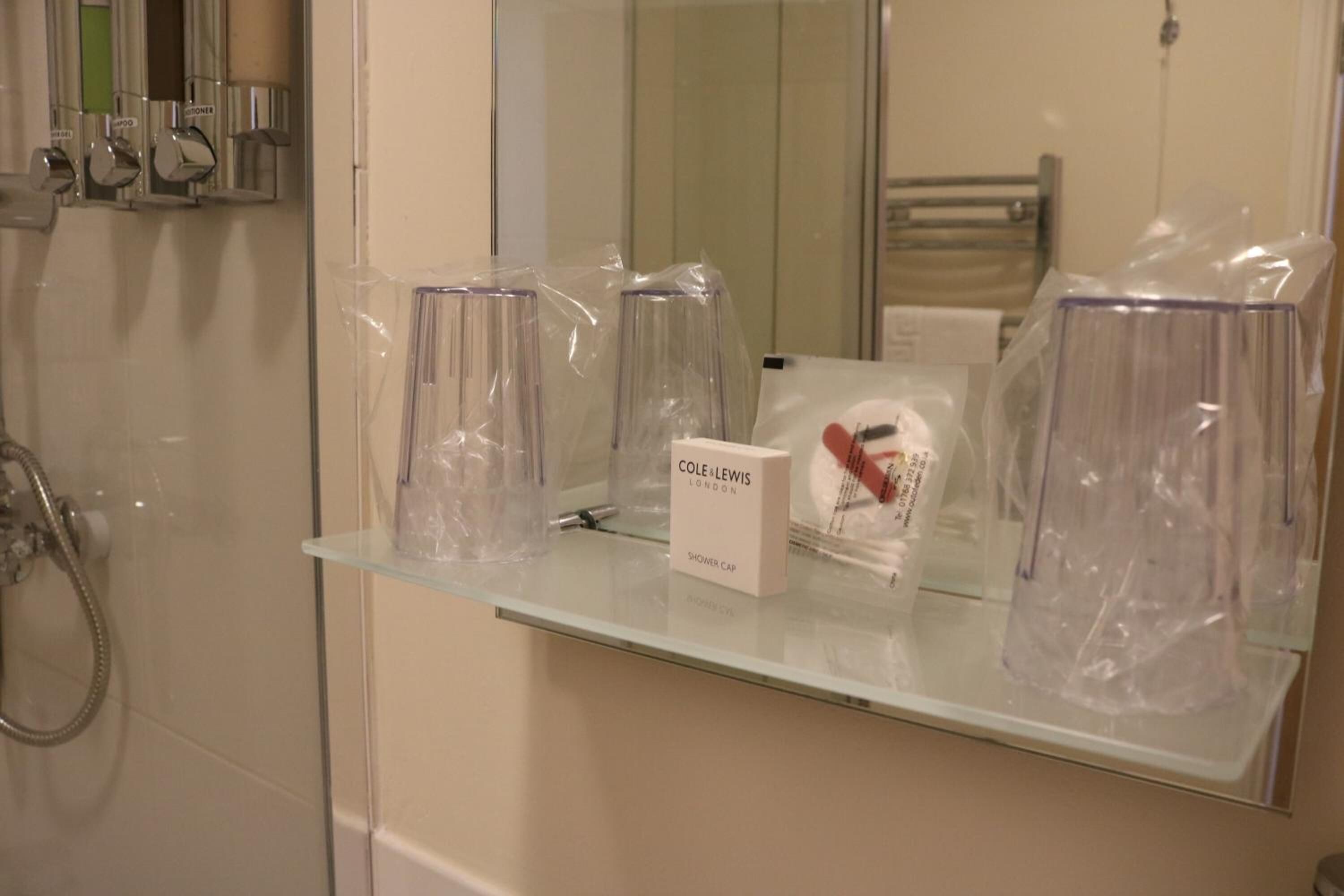 Ein Badezimmer mit Ablagefläche aus Glas, auf der eine Duschhaube und eine Lotionflasche stehen.