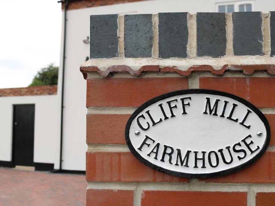Un muro de ladrillo con un letrero que dice 'CLIFF MILL FARMHOUSE'.