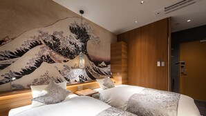 A hotel room with a large traditional Japanese wave painting on the wall, a wooden headboard, and two beds with patterned bedding.