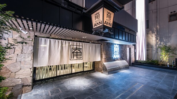 A hotel entrance with stone walls, a covered entrance, and illuminated signage. - Hotel Ann Asakusa (Tokyo)