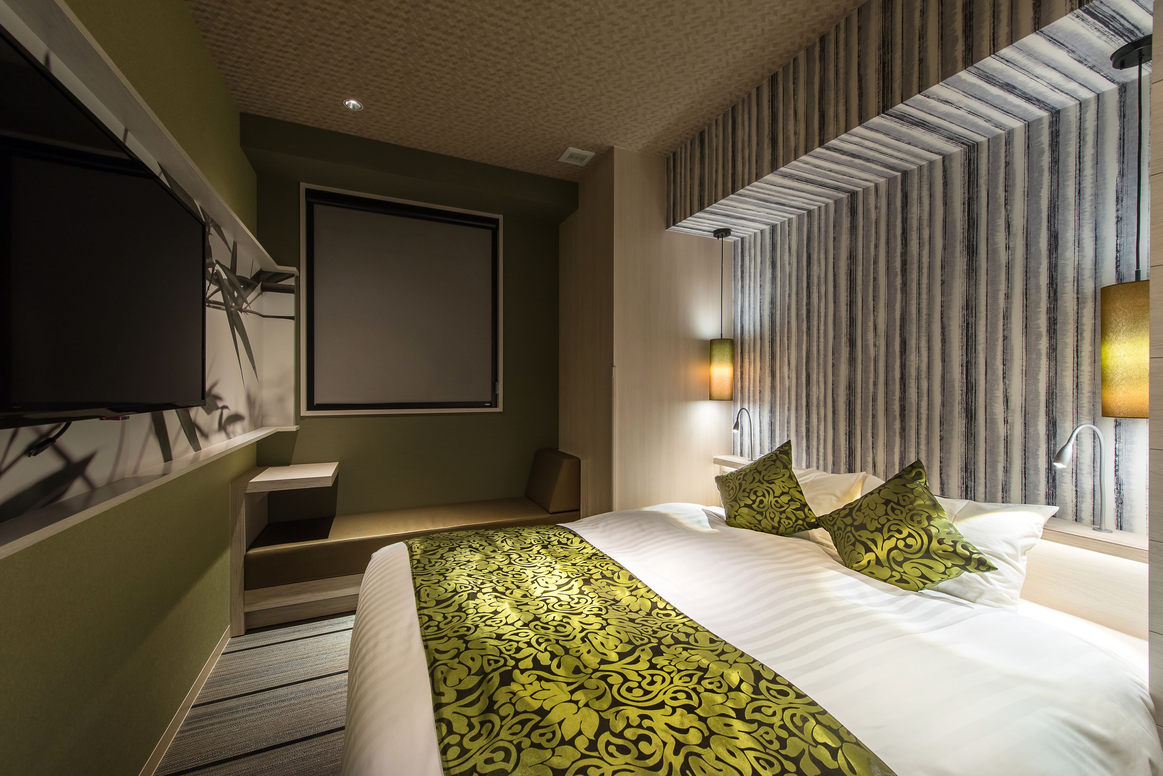 A modern hotel room with a large bed, a flat-screen TV mounted on the wall, and a staircase leading to an upper level.