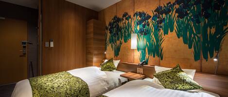 A hotel room with two beds, a wooden headboard, a large floral mural, and a modern light fixture.