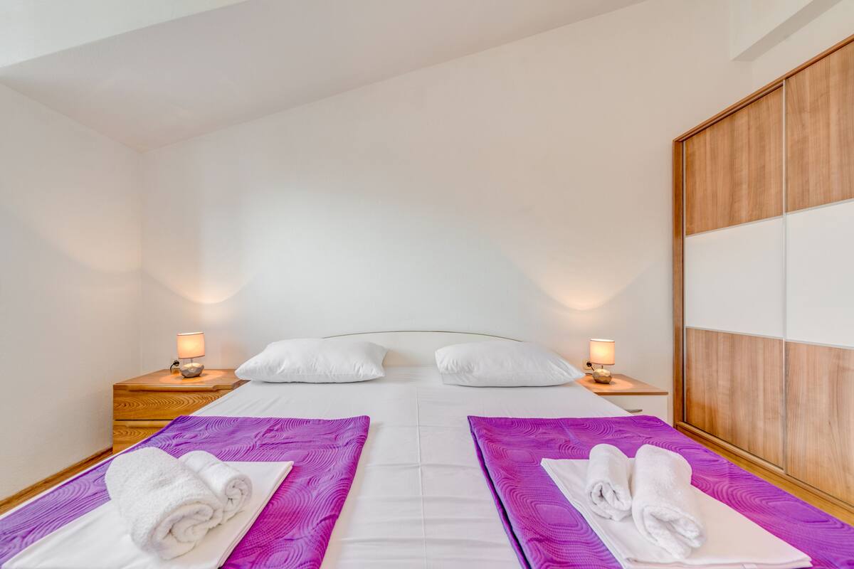 A hotel room with a large bed, two bedside tables with lamps, and a wooden headboard.