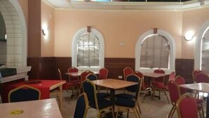 A restaurant interior with tables and chairs, arched windows, and a tiled floor. - Solomon Castle Hotel Mombasa (Mombasa)