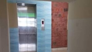 An elevator with a metallic interior and a red brick wall adjacent to it. - Solomon Castle Hotel Mombasa (Mombasa)