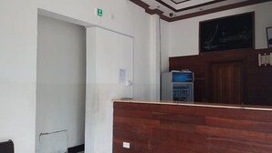 A reception area with a wooden counter, a refrigerator, a water dispenser, and a chalkboard on the wall. - Solomon Castle Hotel Mombasa (Mombasa)