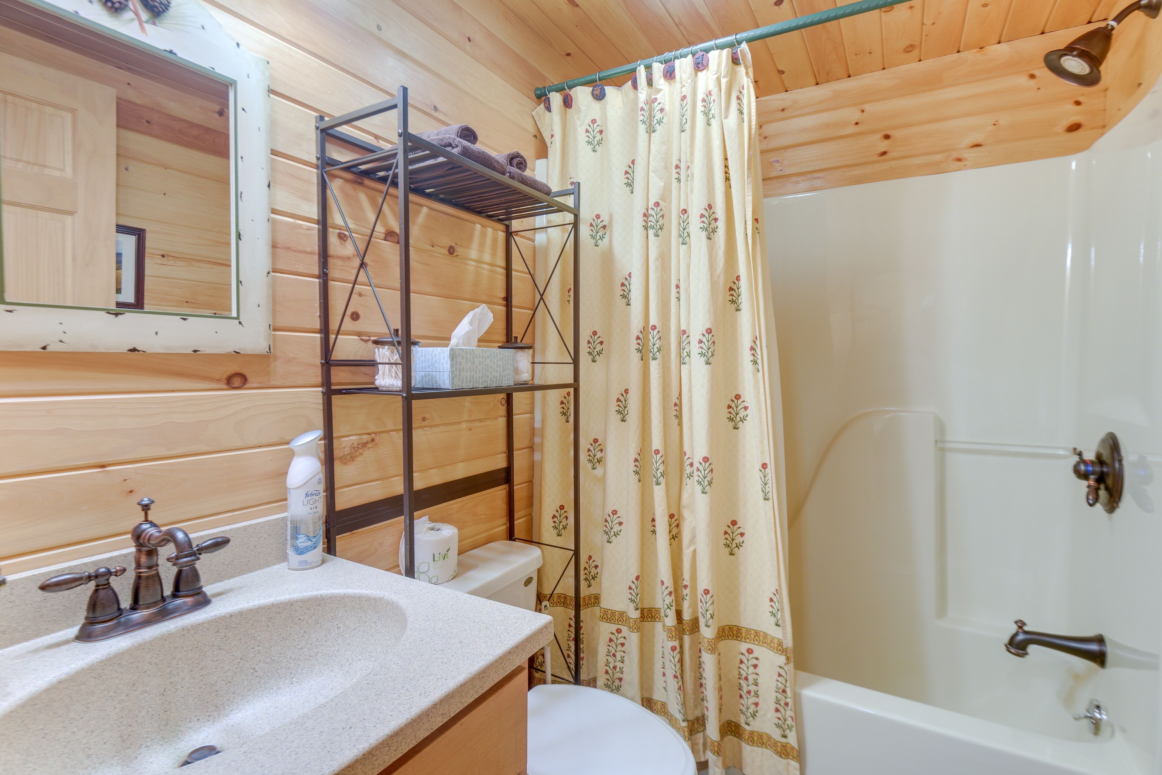 Un baño de cabaña de madera con lavamanos, inodoro y ducha.