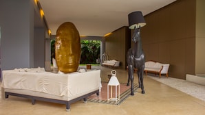 En modern hotellobby med en säng, en stor gyllene skulptur, en svart häststaty, en vit lampa och en sittgrupp.
