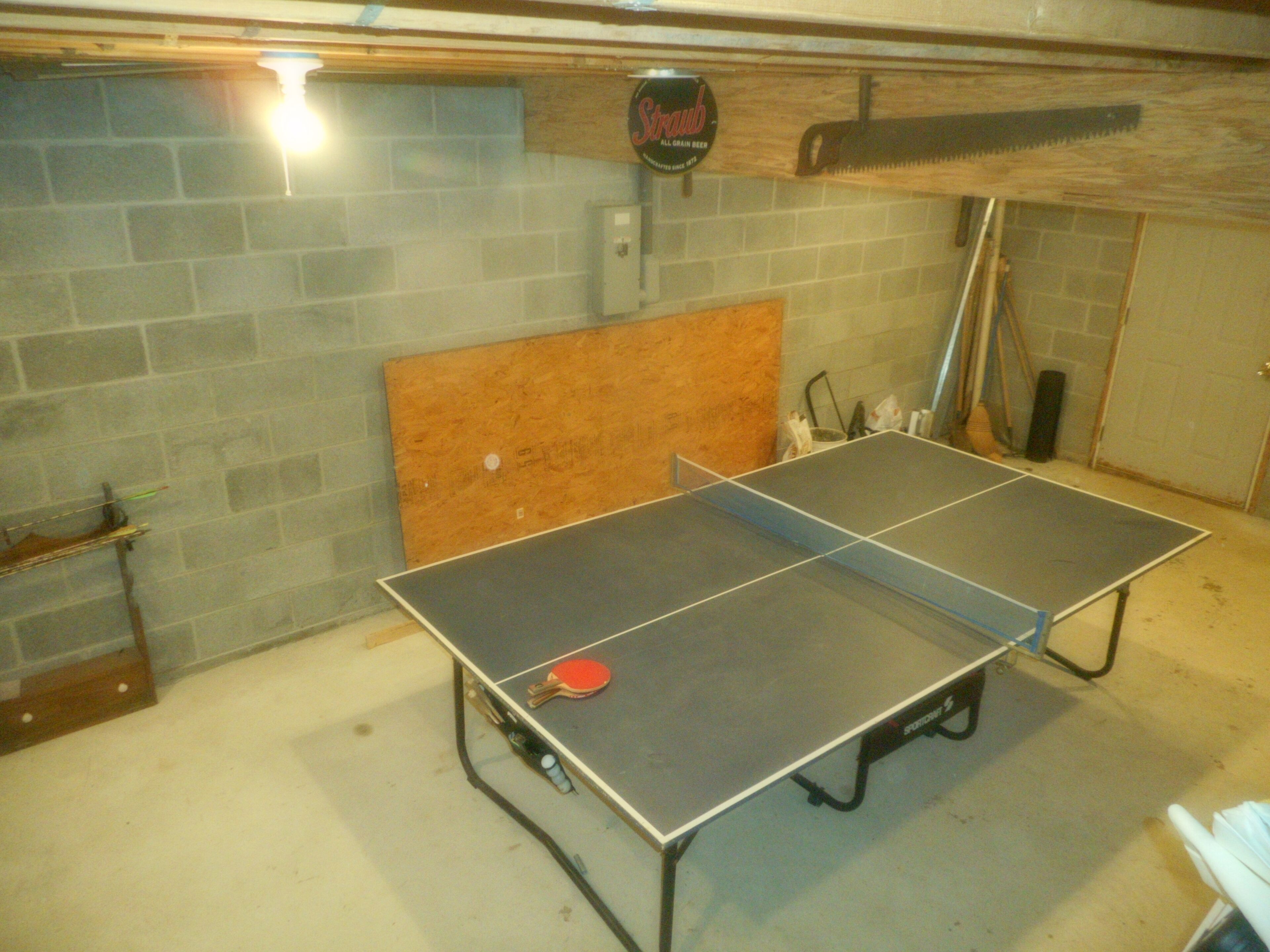 Une table de ping-pong dans une pièce dont les murs sont en briques et le plafond en bois.