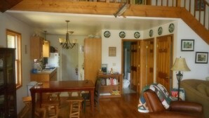 A spacious living area with a wooden staircase, a dining table, and a leather sofa. - Mountain views, total seclusion Southern Bedford County, PA - Big Discounts! (Clearville)