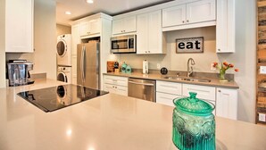 A modern kitchen with white cabinets, stainless steel appliances, and a central island.