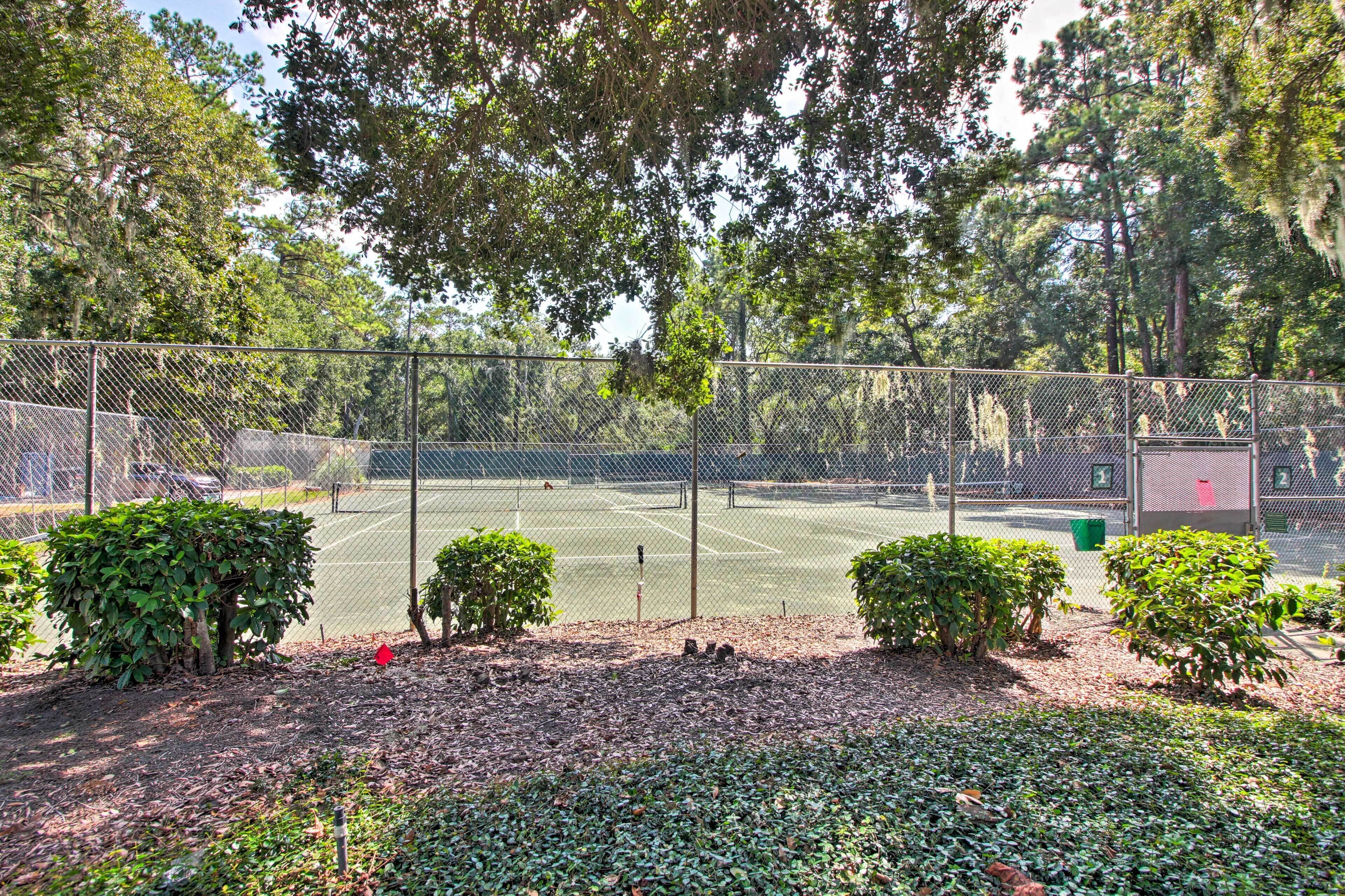 Un campo da tennis circondato da alberi e cespugli.