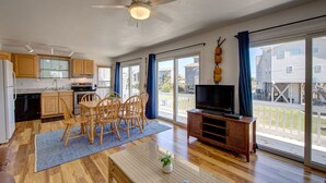 Un amplio espacio habitable con una mesa de comedor, sillas, un televisor de pantalla plana y un ventilador de techo.