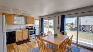 Una cocina con armarios de madera, estufa y comedor con mesa y sillas.