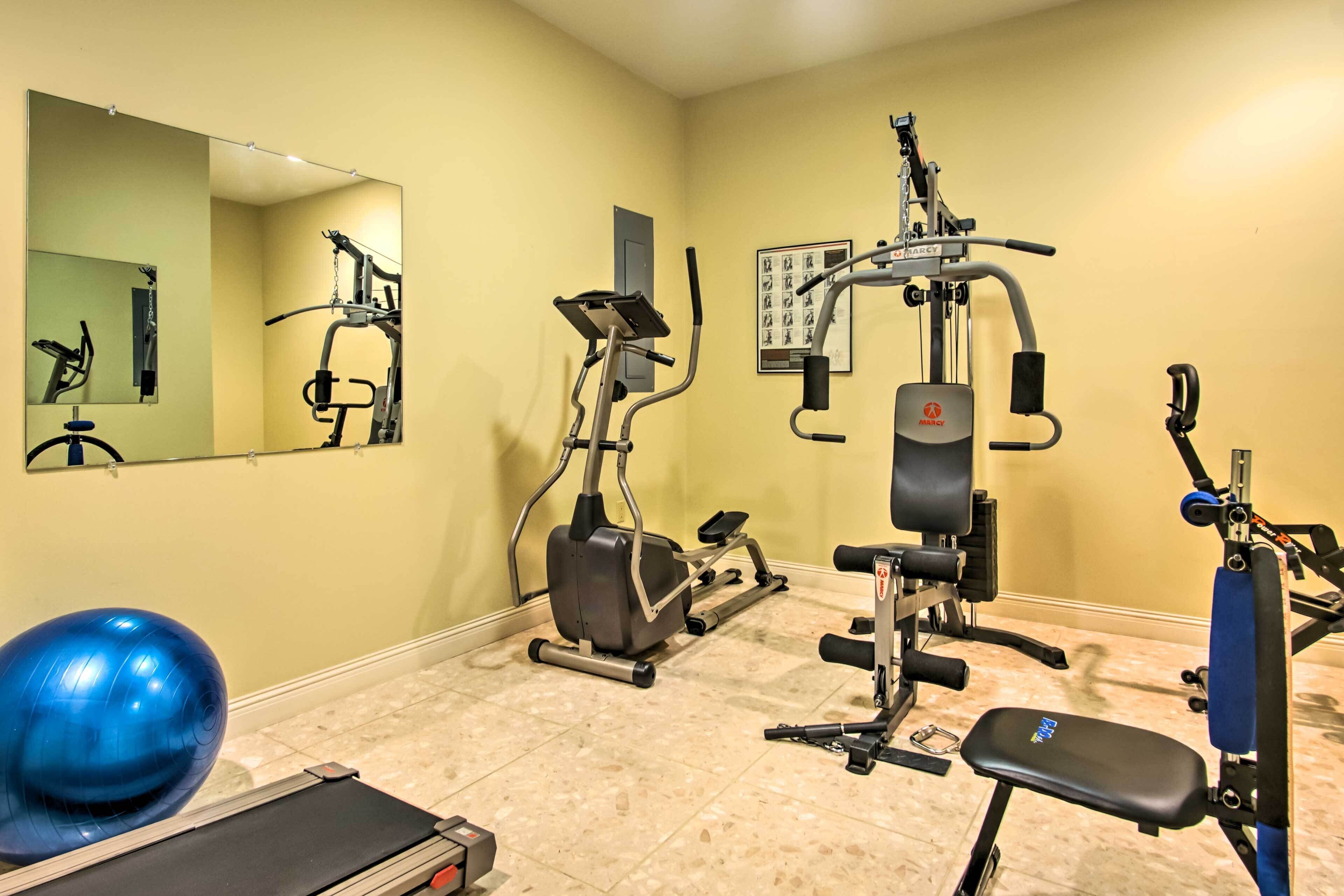 A gym with exercise equipment, a treadmill, and a blue exercise ball.