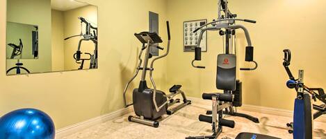 A gym with exercise equipment, a treadmill, and a blue exercise ball.