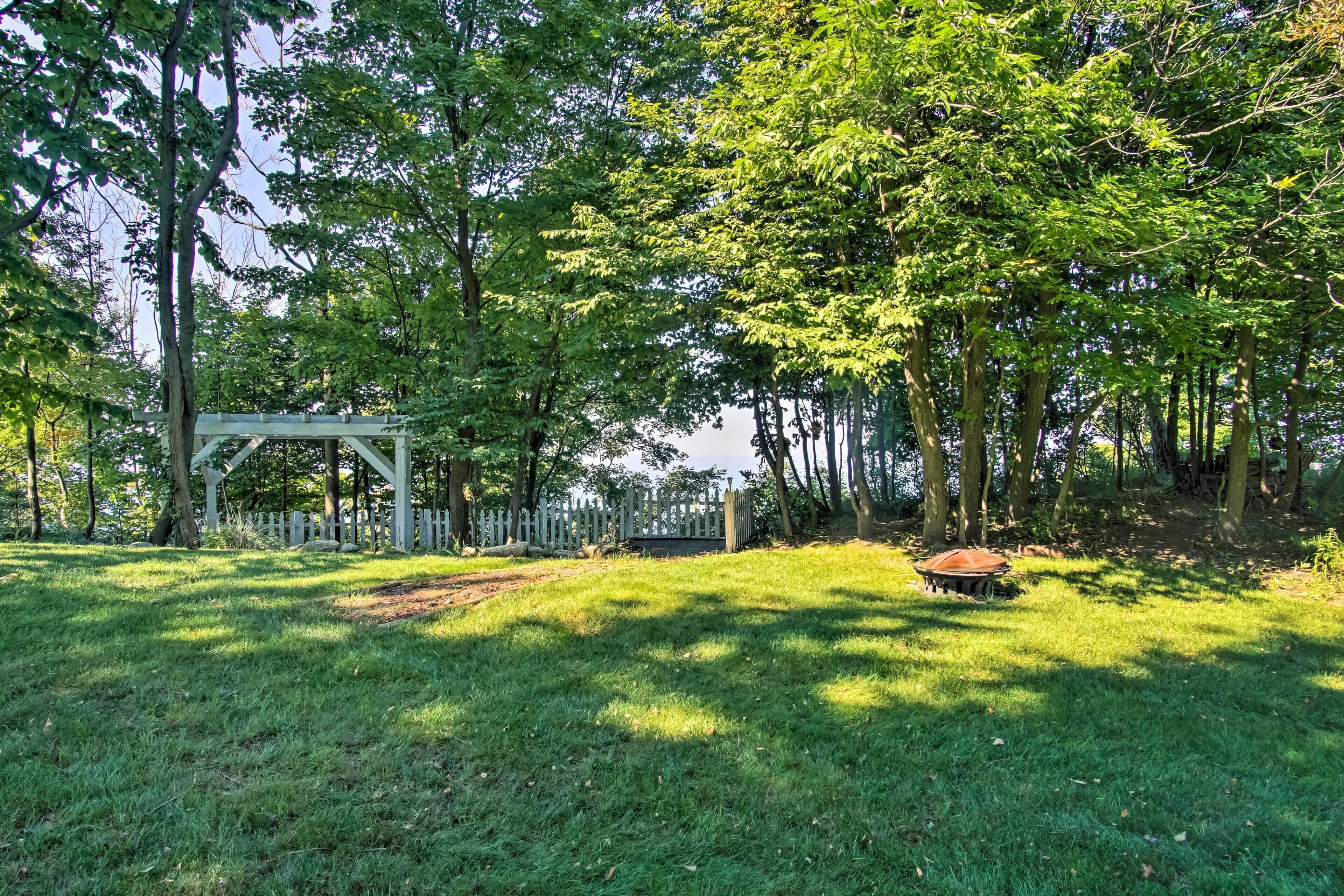 A park with a wooden pergola, a picnic table, and a white picket fence.