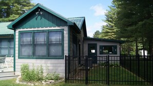 A two-story house with a green roof and a black metal fence.
