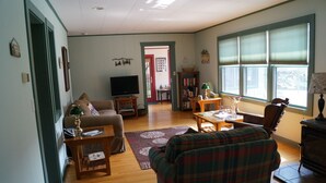 A living room with a sofa, a coffee table, a television, a fireplace, and a bookshelf.