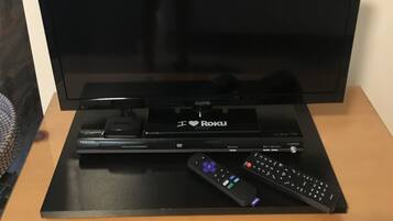 A television on a wooden stand with a remote control and a cable box labeled "I ♥ Roku".