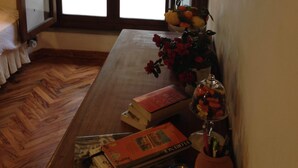 Eine gemütliche Leseecke mit einem Holztisch, Büchern, einer Blumenvase, einer Kerze und einem Fenster mit Rollläden.