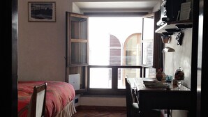 Ein Zimmer mit Bett, Schreibtisch, Stuhl, Fenster und Tür.