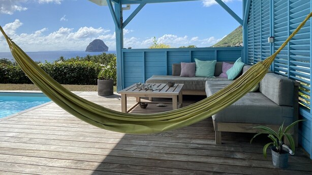 A hammock on a wooden deck with a pool, a sofa with cushions, and a view of the ocean and a small island. - pool, 100 m from the beach, sea, relaxation and standing facing Diamond Rock (Le Carbet)