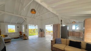 A spacious living area with a high ceiling, a wicker sofa, and a view of the outdoors. - pool, 100 m from the beach, sea, relaxation and standing facing Diamond Rock (Le Carbet)