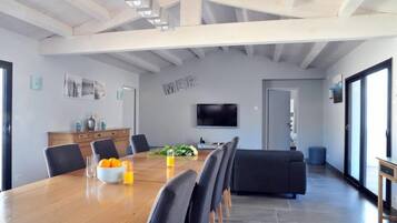 A modern dining area with a wooden table, chairs, and a black sofa.