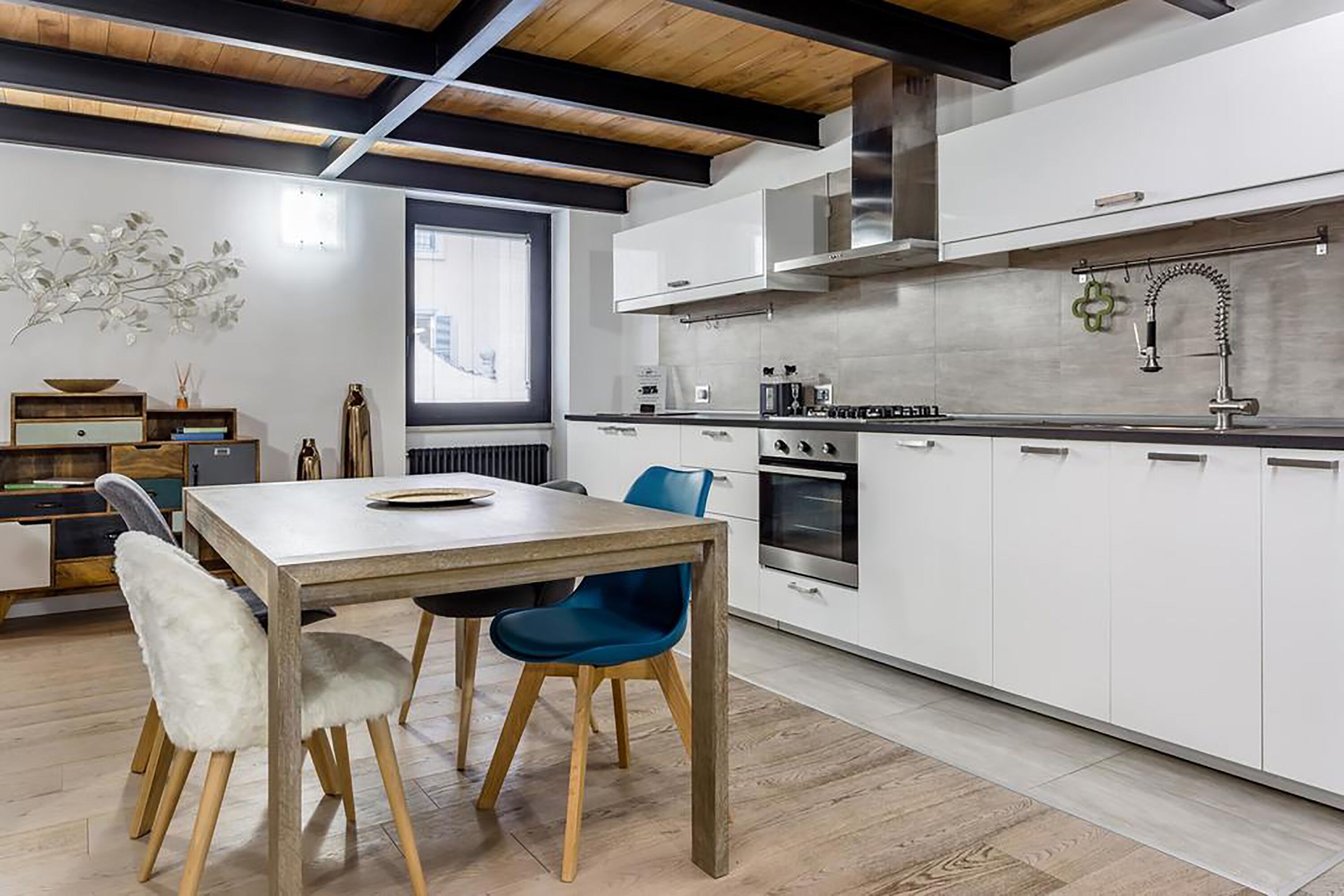 Une cuisine moderne avec des armoires blanches, une hotte de cuisinière en acier inoxydable et un plan de travail noir.
