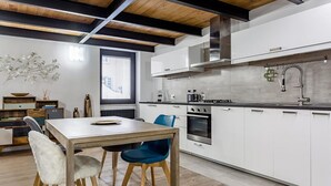 A modern kitchen with white cabinets, a stainless steel range hood, and a black countertop.