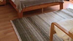 Une chambre à coucher bien rangée, avec un grand lit, une chaise, une carte accrochée au mur et une table de chevet.