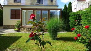 Une maison à deux étages avec un balcon, un rosier et une pelouse.